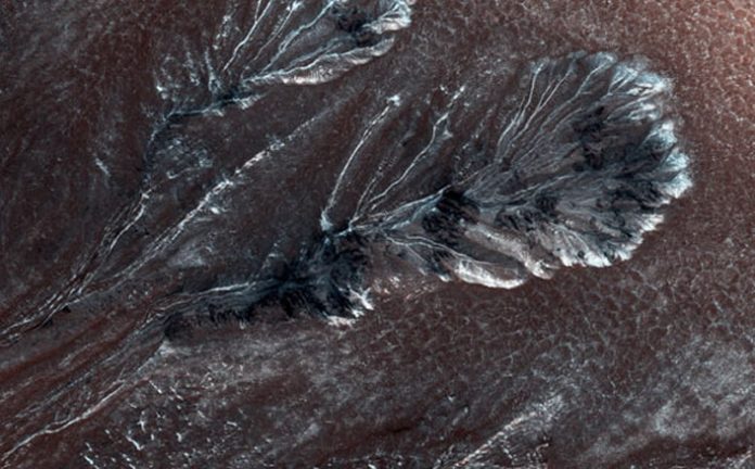 Esta nueva imagen del Orbitador de Reconocimiento de Marte de la NASA muestra la escarcha formada en los barrancos en uno de los cráteres de las llanuras del norte de Marte.